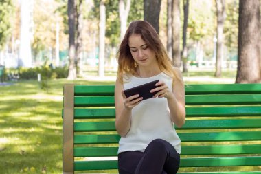 Genç kadın parkta onun tablet kullanma