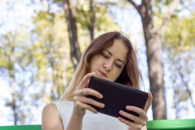 Genç kadın parkta onun tablet kullanma