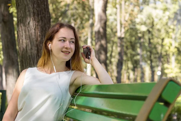 Kvinna som lyssnar på musik i parken — Stockfoto
