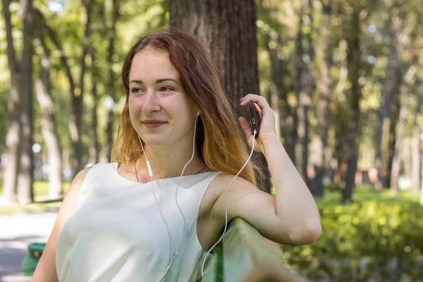 Kvinna som lyssnar på musik i parken — Stockfoto