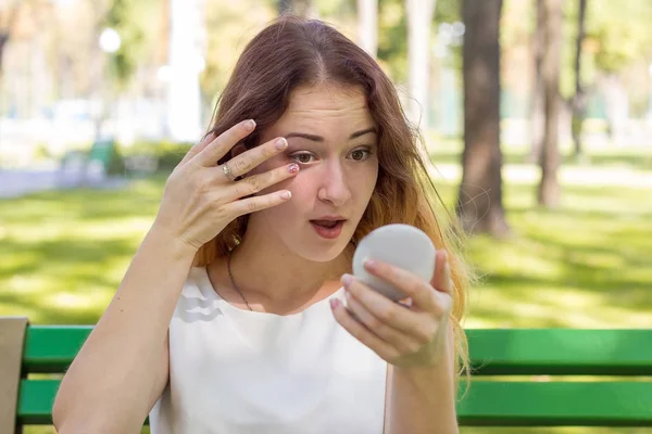 Mujer aplicando maquillaje con el espejo en el parque — Foto de Stock