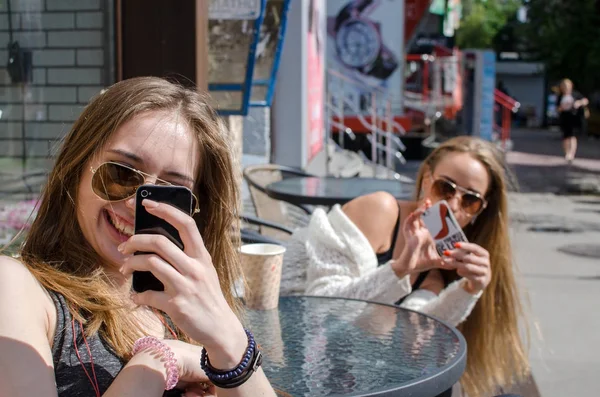 Två väninnor använder mobiltelefoner — Stockfoto