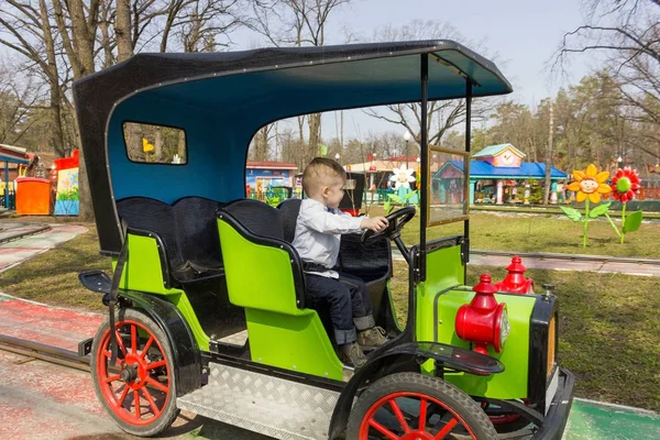 Niño con camisa está conduciendo un carro verde — Foto de Stock