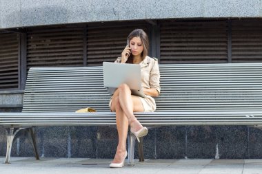 dizüstü bilgisayar ile bankta oturan kadın