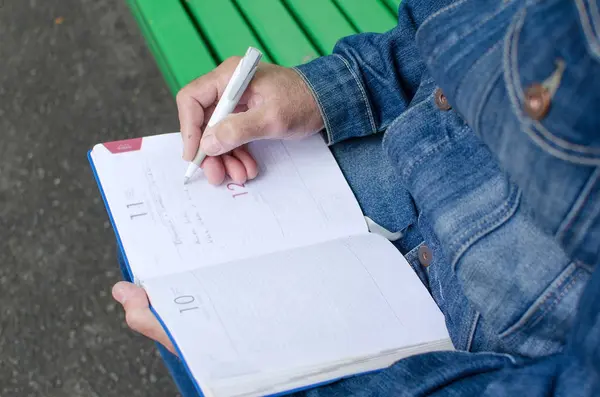 Hombre de edad está tomando notas en el planificador diario — Foto de Stock