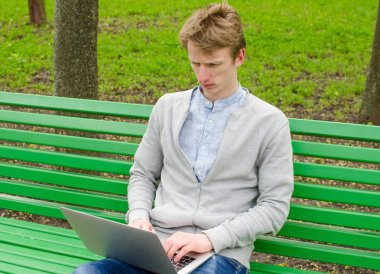 Genç adam laptopunu kullanıyor.