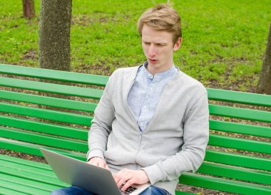 Genç adam laptopunu kullanıyor.