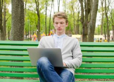 Genç adam laptopunu kullanıyor.