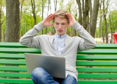 Genç adam laptopunu kullanıyor.