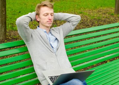 Genç adam laptopunu kullanıyor.