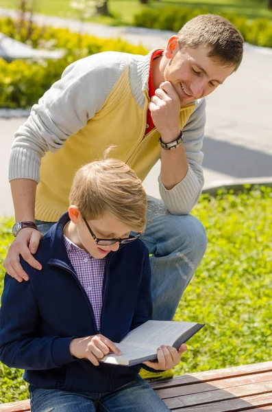 Young man is helping teenager to read a book — Stock Photo, Image