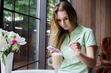 kafede cep telefonunu kullanan kadın