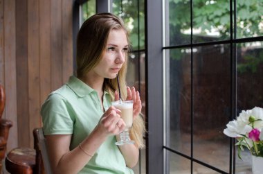 Kadın kafede kahve içiyor.