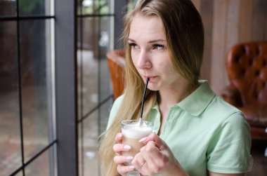 Kadın kafede kahve içiyor.