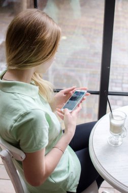 kadın cafede cep telefonunu kullanıyor