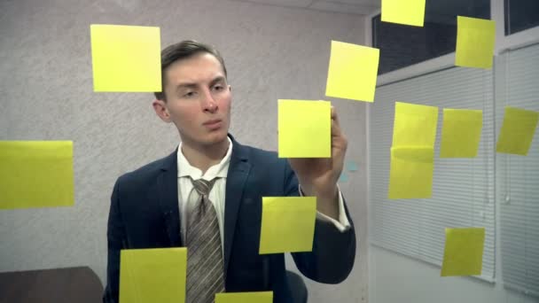 Jeune homme travaillant avec des notes collantes au bureau — Video