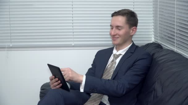 Бизнесмен работает над планшетом на диване в офисе — стоковое видео