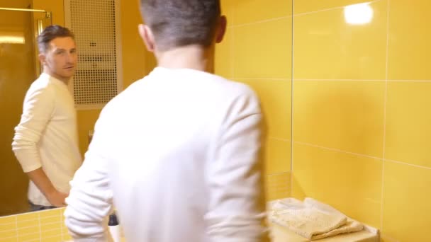 Genç adam tuvalete aynaya bakarak — Stok video