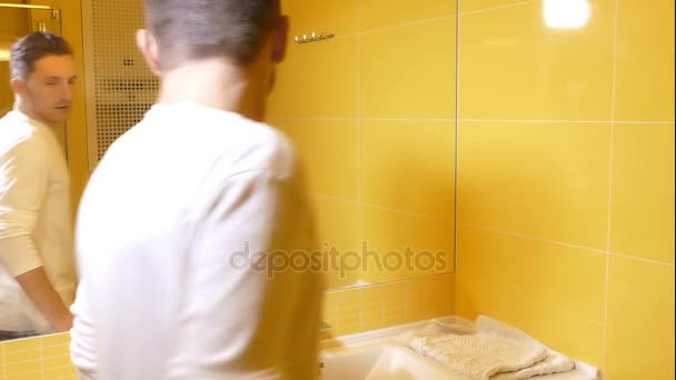 Молодой человек смотрит на зеркало в ванной утром — стоковое видео