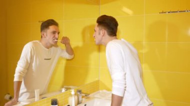 Genç adam sabahları dişlerini fırçalıyor.