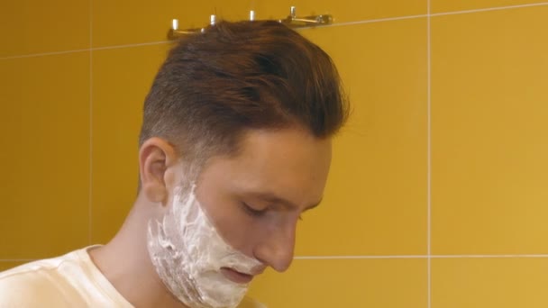 Closeup of young man shaving in the bathroom in front of mirror — Stock Video