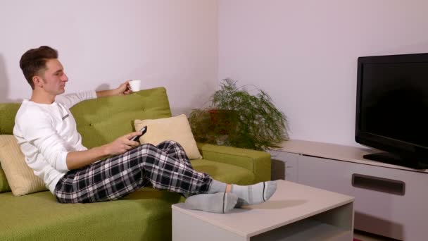 Hombre guapo viendo la televisión en su sala de estar — Vídeo de stock