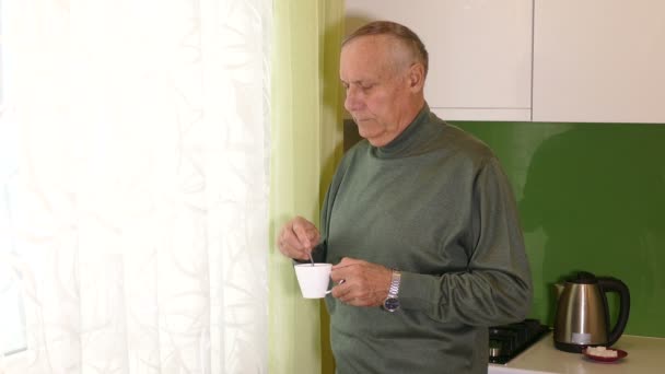 Hombre viejo mirando a la ventana con taza de té en las manos — Vídeo de stock