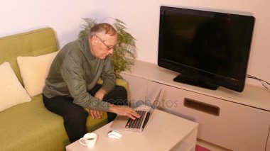 Eski oturma odasında dizüstü bilgisayar kullanan adam