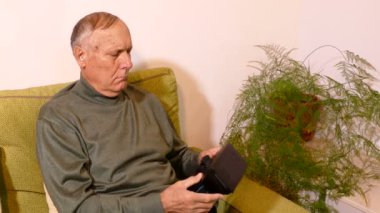 İhtiyar oturma odasında kanepede oturan ve tablet kullanma