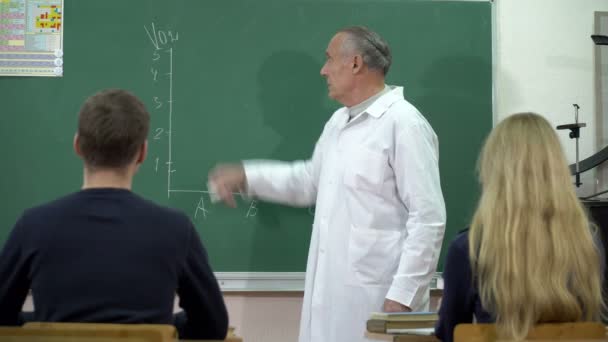 Um professor universitário escreve um novo tópico na lousa para seus alunos — Vídeo de Stock