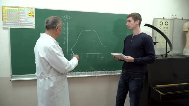 Kolega profesor zobrazení grafiky na studenta na tabuli — Stock video