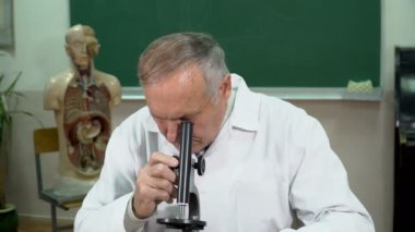 Sınıf mikroskobu ile çalışan bir üniversite profesörü