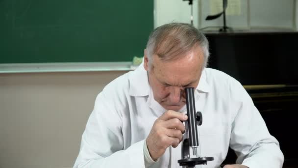 Крупный план преподавателя колледжа, работающего с микроскопом в классе — стоковое видео
