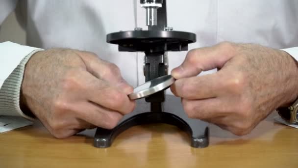 Closeup of college professor adjusting the mirror of microscope in the classroom — Stock Video