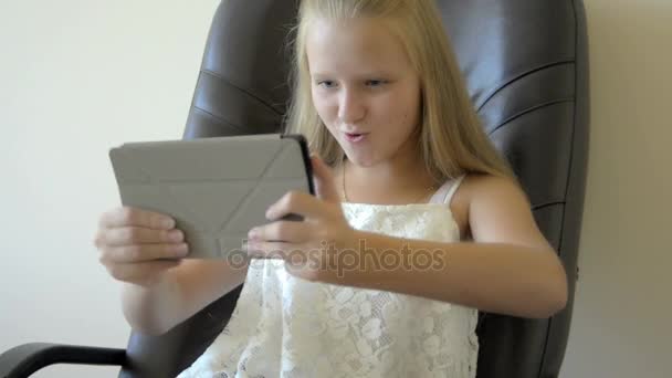 Vista frontal de adolescente niña sentada y jugando con la tableta — Vídeos de Stock