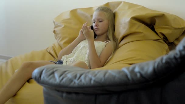 Blondes Teenager-Mädchen sitzt und telefoniert — Stockvideo