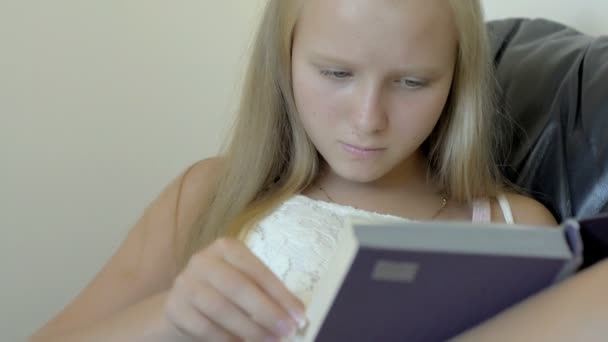 Nahaufnahme eines Teenagers, der ein Buch auf der Couch liest — Stockvideo