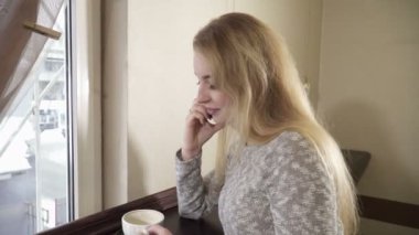 kafede oturan ve telefonda konuşurken genç kadın