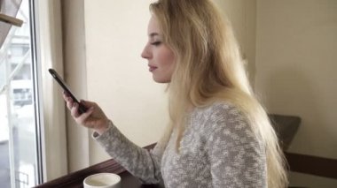 kafede oturan ve cep telefonunu kullanarak genç kadın