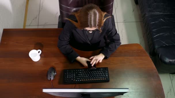 Bovenaanzicht jonge vrouw te typen op de mobiele telefoon in kantoor — Stockvideo