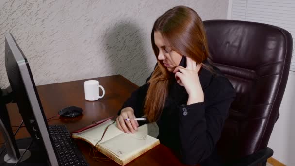 電話での会話、オフィスでノートを作って若い実業家 — ストック動画