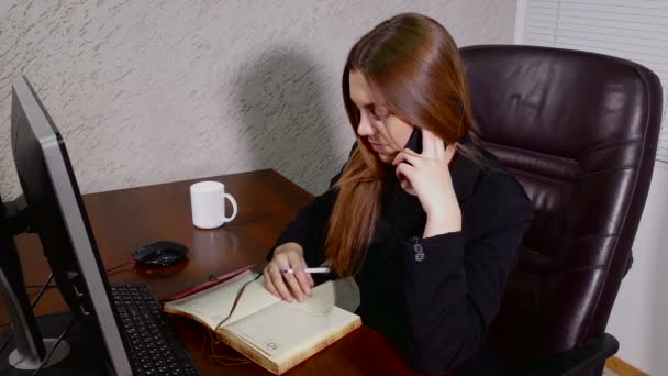 Giovane donna d'affari che parla al telefono e prende appunti in ufficio — Video Stock