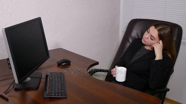 Tired Young woman drinking in from of computer in office — Stock Video