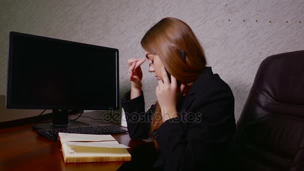 Jonge zakenvrouw praten aan de telefoon en het maken van aantekeningen in notitieblok — Stockvideo