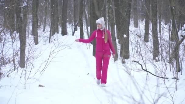 Mujer rubia joven caminando en el bosque de invierno — Vídeos de Stock