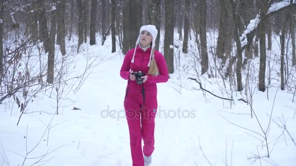 Mujer rubia joven haciendo fotos con cámara fotográfica en el bosque de invierno — Vídeos de Stock