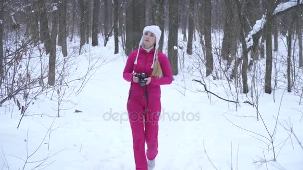 Unga blonda kvinnan att göra bilder med photocamera i vinter skog — Stockvideo