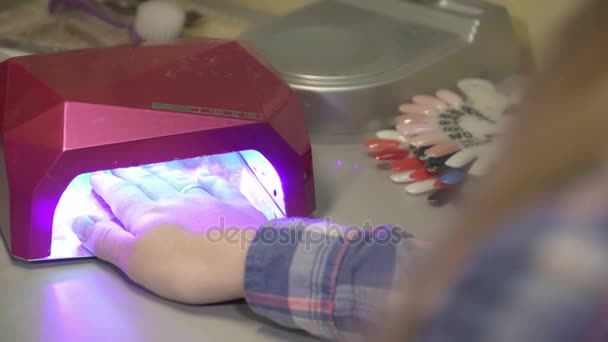 Jong meisje droogt in de lamp manicure nagels — Stockvideo