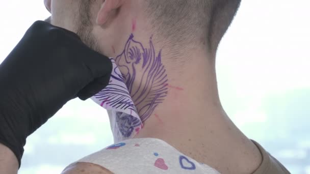 Tatooer face o schiță pe gâtul tânărului bărbat — Videoclip de stoc