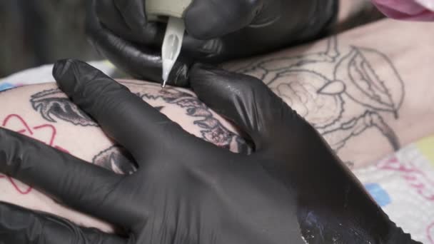 黒手袋で Tatooer はタトゥー マシンとタトゥーを作ってください。 — ストック動画